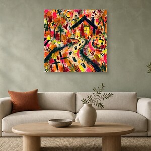 A square abstract artwork hanging unframed on a sage green wall above a beige sofa with a rust-colored pillow, an oval wooden coffee table, and a potted tree.