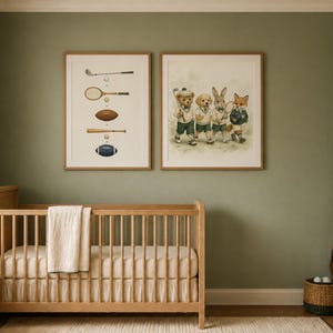 May include: Two framed wall art prints hanging above a wooden crib. One print displays various sports equipment including a golf club, tennis racket, football, and baseball bat. The second print features a bear, dog, rabbit, and fox dressed in athletic attire.