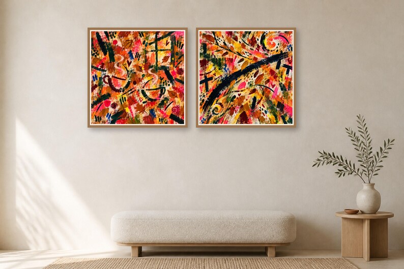 Two framed square abstract art prints with warm colored brush strokes hang on a plain wall above a long low bench.