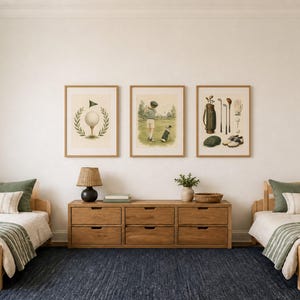 May include: Three framed wall art prints featuring golf themes, including a golf ball on a tee, a person playing golf, and a collection of golf equipment, displayed above a wooden dresser between two twin beds with green and white bedding.