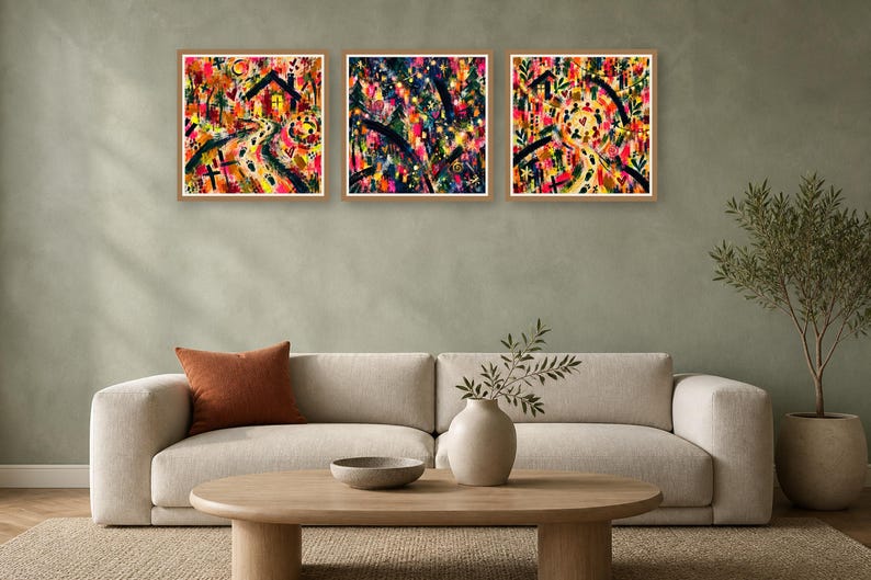 Three framed square abstract art prints with colorful gestural strokes hang above a modern beige sofa in a minimalist living room.