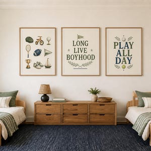 Puede incluir: Tres cuadros de pared con ilustraciones de equipamiento deportivo, un velero y el texto "LONG LIVE BOYHOOD" y "PLAY ALL DAY" en verde oscuro y azul, colocados sobre una c&oacute;moda de madera entre dos camas individuales con cojines verdes.