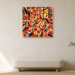 Minimalist room setup featuring a single square abstract colorful art print hung above a long neutral bench and a small plant.