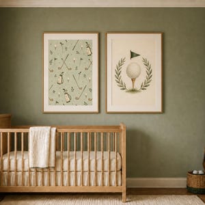 Two framed nursery prints hang over a wooden crib against a sage green wall in a styled baby room.