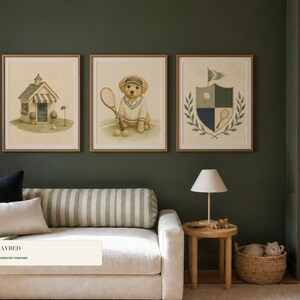 May include: Three framed wall art prints featuring a golf-themed illustration set. The left print shows a small clubhouse, the center print depicts a golden retriever puppy holding a tennis racket, and the right print displays a golf crest shield.