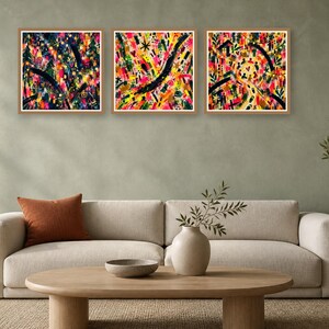 Three framed square abstract artworks with bold expressive brush strokes mounted on a wall above a contemporary sofa.