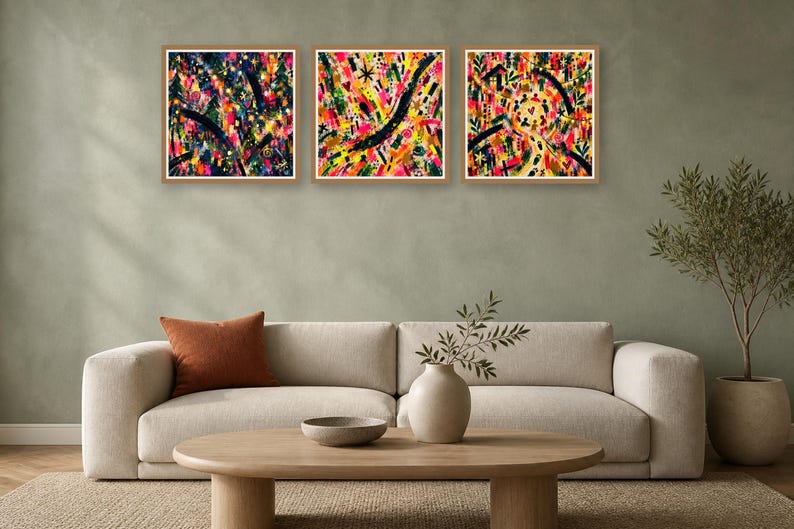 Three framed square abstract artworks with bold expressive brush strokes mounted on a wall above a contemporary sofa.