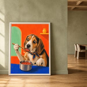 A framed art print of a beagle cooking is displayed on a wooden floor against a sage green wall.