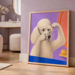 A framed art print of a white poodle cutting its own hair with scissors leans against a purple wall in a room with a white ottoman and vanity table.