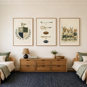 May include: Three framed wall art prints displayed above a wooden dresser between two twin beds. The prints feature a sports crest, a collection of vintage sports equipment, and an illustration of a bear, dog, rabbit, and fox dressed in athletic gear.