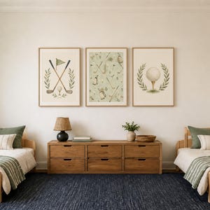 Two twin wooden beds with green bedding flank a long wooden dresser beneath three framed golf art prints hanging on a neutral wall.