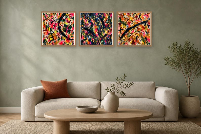 A neutral living room features a beige sofa with an orange pillow, a wood coffee table, and three matching square abstract art prints in light wood frames hung on a green wall.