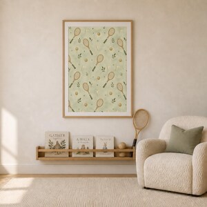The tennis racket pattern print hangs in a wood frame above a children's bookshelf and an armchair.