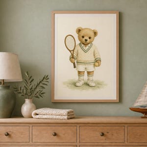 May include: A framed wall art print featuring a light brown teddy bear dressed in a cream-colored cable knit sweater with green trim, white shorts, and white sneakers, holding a wooden tennis racket while standing on a patch of green grass.