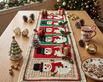 May include: A rectangular crochet table runner featuring a repeating pattern of snowmen with black top hats, orange carrot noses, and red scarves, framed by alternating red and green borders on a cream-colored background with a textured finish.