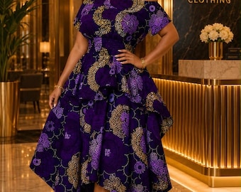 May include: A purple off-the-shoulder dress featuring a gold and dark purple circular pattern. The garment has short sleeves, a cinched waist with a smocked detail, and a layered, asymmetrical high-low skirt that falls below the knees.