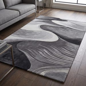 May include: A rectangular area rug featuring a high-low pile texture with an abstract pattern of flowing, organic shapes in shades of charcoal, slate gray, silver, and white, creating a layered, dimensional appearance across the surface.