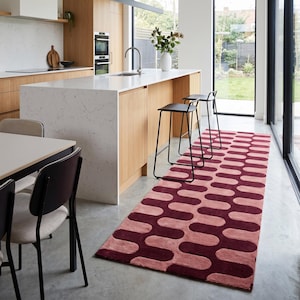 Puede incluir: Una alfombra de pasillo rectangular con un patrón repetitivo de formas onduladas redondeadas entrelazadas en tonos alternos de burdeos intenso y rosa empolvado, colocada sobre un suelo de hormigón liso en una cocina.