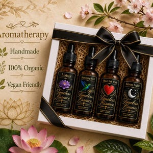 May include: A white gift box containing four amber glass dropper bottles labelled Timeless Essence with the names Lotus, Humming bird, Heart Felt Wish, and Moon Light. The box is tied with a black ribbon and includes text about aromatherapy.