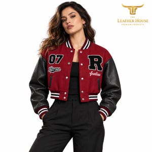 Puede incluir: Una chaqueta universitaria corta con cuerpo de lana color granate y mangas de cuero negro. El frente muestra el número 07, la palabra Players, una letra R grande y la palabra fearless bordadas en blanco, con botones de presión plateados.