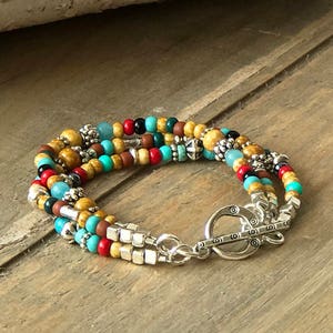 May include: Multi-strand bracelet with wooden, turquoise, red, and silver beads. The bracelet has a silver clasp.