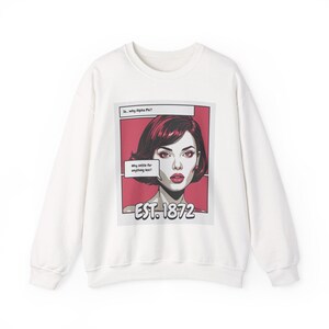 May include: A white long-sleeve sweatshirt featuring a pop art graphic of a person with dark hair on a red background. The text reads: So... why Alpha Phi? Why settle for anything less? EST. 1872. The design is framed in a rectangular border.