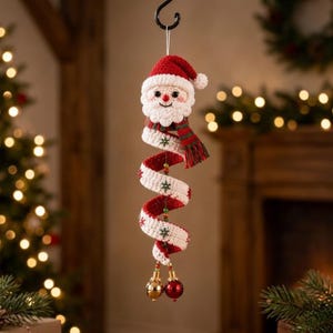 May include: A crocheted Santa Claus ornament featuring a spiral body design in red and white yarn. The Santa head wears a red hat and a striped scarf. The spiral body is decorated with small green snowflake accents and ends with two shiny jingle bells.