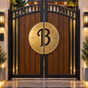 Puede incluir: Una puerta doble con paneles verticales de aspecto madera enmarcados en metal negro con una parte superior arqueada. Una gran placa circular dorada está centrada en la puerta, mostrando la letra B, el texto BRA BOO, EST. 2026 e INSPIRED FLAVORS.