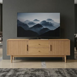 May include: A light oak wood media console featuring two side cabinets with vertical fluted door panels and two central stacked drawers with small round knobs. The unit is supported by four tapered legs and sits beneath a flat-screen television.