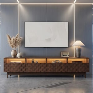 May include: A long, dark brown wooden media console with a textured, square-patterned front and integrated interior lighting. The console features four storage sections, a flat top surface, and is positioned against a gray wall with a mounted television.
