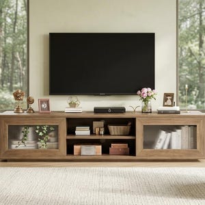 May include: A long, light brown wooden media console featuring two side cabinets with vertical reeded glass doors and a central open shelving unit. The console is positioned beneath a large, flat-screen television mounted on a light-colored wall.