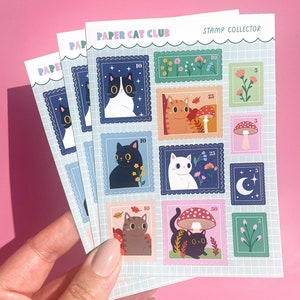 A rectangular A6 sheet of matte stickers featuring various designs of cats nestled among wildflowers, styled as postage stamps.