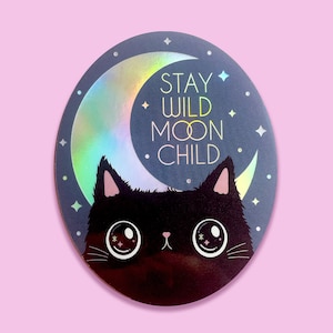 May include: A black cat with large eyes sits in front of a crescent moon with a holographic finish. The moon has the text "Stay Wild Moon Child" on it.