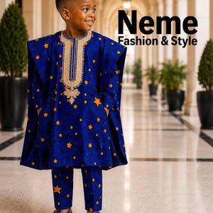 May include: A blue long-sleeved tunic and matching trousers featuring an orange star pattern and gold embroidery around the neckline. The text Neme Fashion & Style is visible in the upper right corner of the image. The outfit includes brown loafers.