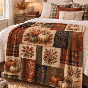 May include: A rectangular throw blanket featuring a patchwork design of autumn-themed illustrations. The pattern includes orange, white, and green pumpkins, brown oak leaves, wheat stalks, red berries, and plaid fabric squares in shades of brown and red.