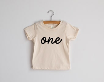 One First Birthday Organic Kids T-Shirt • Modern Script Lettered Shirt for Trendy One Year Olds • Natural Cream Organic Birthday Tee