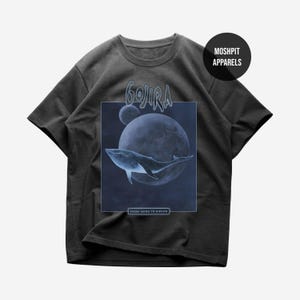 Puede incluir: Una camiseta gris carbón de manga corta con un estampado gráfico de una ballena nadando frente a un planeta grande y una luna más pequeña. El texto GOJIRA aparece sobre el gráfico y FROM MARS TO SIRIUS está impreso en un recuadro debajo.
