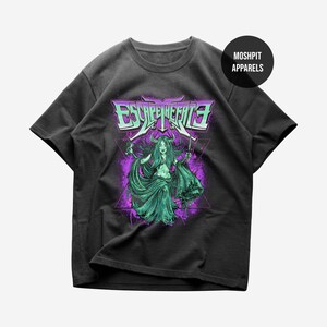 May include: A black short-sleeve t-shirt featuring a graphic print of a horned figure with long hair holding a dagger. The text ESCAPE THE FATE is printed in a stylized font above the figure, with purple accents and a black circle logo.
