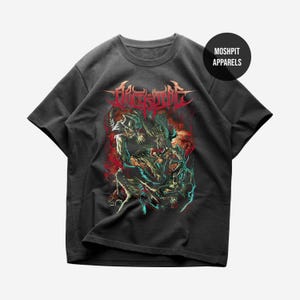 May include: A charcoal gray short-sleeve t-shirt featuring a graphic print of a multi-limbed creature in red, blue, and white tones. The text MOSHPIT APPARELS appears in a black circle in the upper right corner, with stylized lettering above the creature.