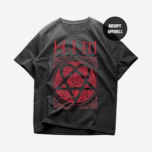 May include: A black short-sleeve t-shirt featuring a red graphic print. The design includes the text "HIM" at the top, a circular emblem filled with red roses, and decorative corner flourishes. A black circular badge reads "MOSH PIT APPARELS".