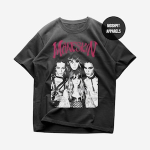 Könnte beinhalten: Ein anthrazitfarbenes Kurzarm-T-Shirt mit einem schwarz-weißen Fotodruck der Band Måneskin. Das Wort Måneskin ist in einer großen, stilisierten rosa Schrift über den Bandmitgliedern gedruckt. Ein schwarzes kreisförmiges Logo zeigt MOSHPIT APPARELS.