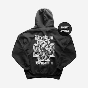 Può includere: Una felpa nera con cappuccio caratterizzata da una grafica bianca sul retro con il testo Breaking Benjamin sopra e sotto un design a nodo stilizzato. Un badge circolare nero sul lato superiore destro contiene il testo bianco MOSHPIT APPARELS.