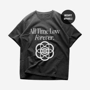May include: A charcoal gray short-sleeve t-shirt featuring the white text All Time Low Forever. Below the text is a white graphic of a stylized flower with an eye in the center. A black circular logo in the top right corner reads MOSHPIT APPARELS.