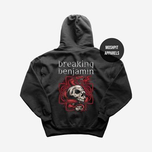 Könnte beinhalten: Ein schwarzer Kapuzenpullover mit einer Grafik auf der Rückseite, die den Text breaking benjamin über einer roten Schlange zeigt, die sich um einen menschlichen Schädel windet. Das Design liegt auf einem roten geometrischen Muster. MOSHPIT APPARELS.
