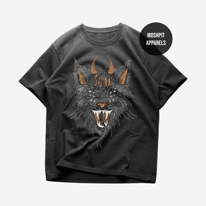 Op de afbeelding: Een zwart t-shirt met korte mouwen en een afbeelding van een gehoornd wezen met meerdere ogen en de tekst "GOJIRA" in oranje. Het ontwerp bevat gedetailleerde witte lijnen en een zwart cirkelvormig logo rechtsboven met "MOSHPIT APPARELS".