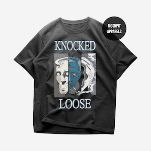 Op de afbeelding: Een antracietgrijs T-shirt met korte mouwen en een grafische print van drie gestileerde gezichten in verticale panelen. De tekst KNOCKED LOOSE staat in lichtblauw boven en onder de afbeelding. Een cirkelvormig logo vermeldt MOSHPIT APPARELS.
