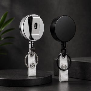 Può includere: Due portabadge retrattili, uno con finitura argento lucido e uno con finitura nero opaco. Ogni avvolgitore circolare presenta una clip da cintura in metallo sul retro, un cordino robusto, un anello portachiavi in metallo e un cinturino in tessuto.