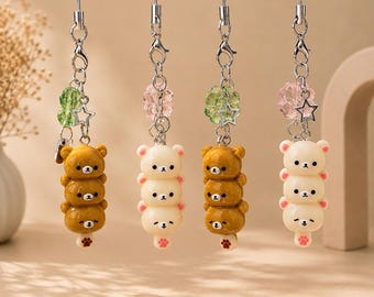 May include: Four phone charms featuring stacks of three bear heads in brown or cream colors. Each charm includes a silver-tone metal chain, a small star-shaped charm, a translucent flower-shaped bead, and a bear paw print detail at the base.