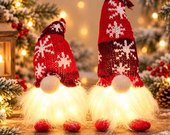 May include: Two gnome figurines with tall, red knit hats featuring white snowflake patterns. Each gnome has a round, light-colored nose and a long, white, fluffy beard that glows with internal warm white LED lights. They have small red feet.