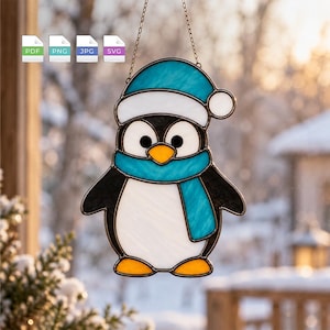 May include: A stained glass suncatcher shaped like a penguin wearing a blue and white winter hat and a matching blue scarf. The penguin has a white belly, black wings, and orange feet and beak. A thin metal chain is attached for hanging.